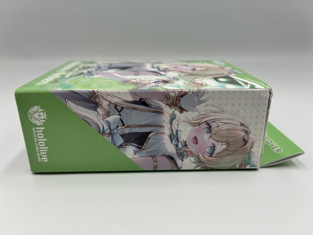 A green rectangular product box with anime-style character artwork printed on the top and side panels, photographed on a light gray studio background. The visible text/logo on the left side reads 'hololive'.