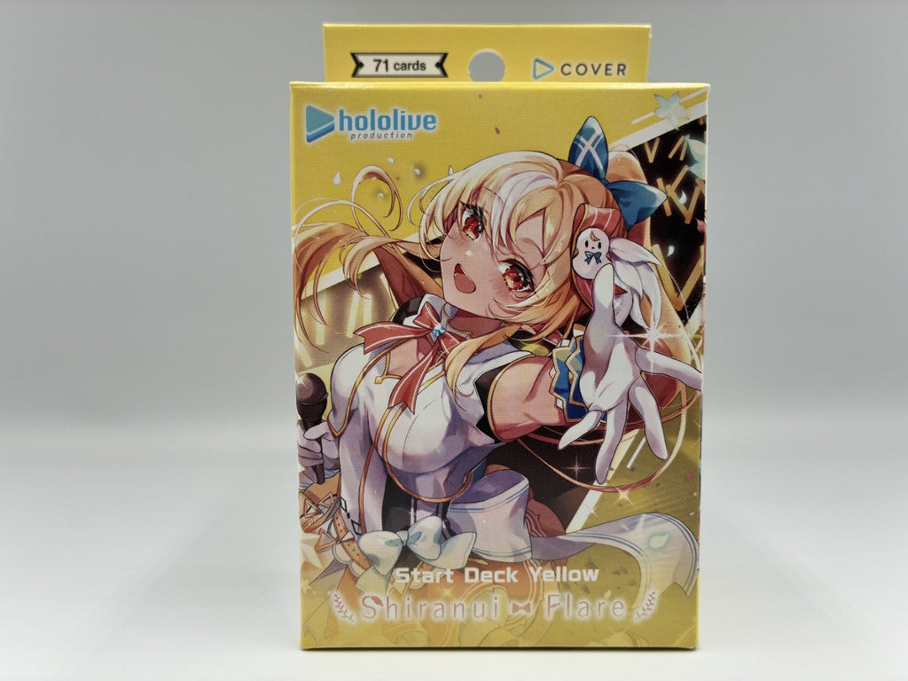 A Hololive Official Start Deck Yellow 'Shirani x Flare' card box, featuring anime artwork of a blonde character with a white rabbit on the front, set against a neutral gray background.