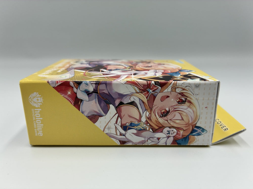 A collectible card box for Hololive anime figures, featuring a yellow side panel with the 'hololive' logo and an illustration of a blonde anime character on the top and front.