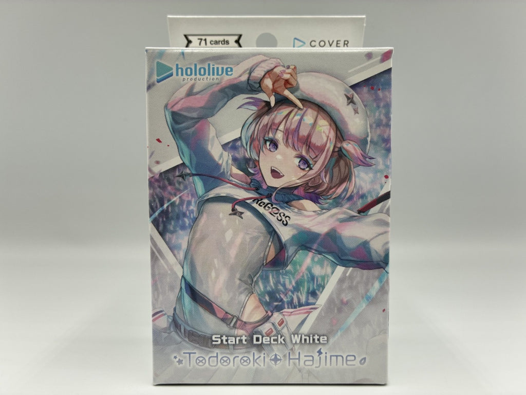 A boxed trading card deck package standing upright on a light gray background. The front shows anime artwork of a girl in a white sailor-style outfit with pink hair, and text reading 'hololive', 'COVER', 'Start Deck White', and 'Todoroki+Hajime'.